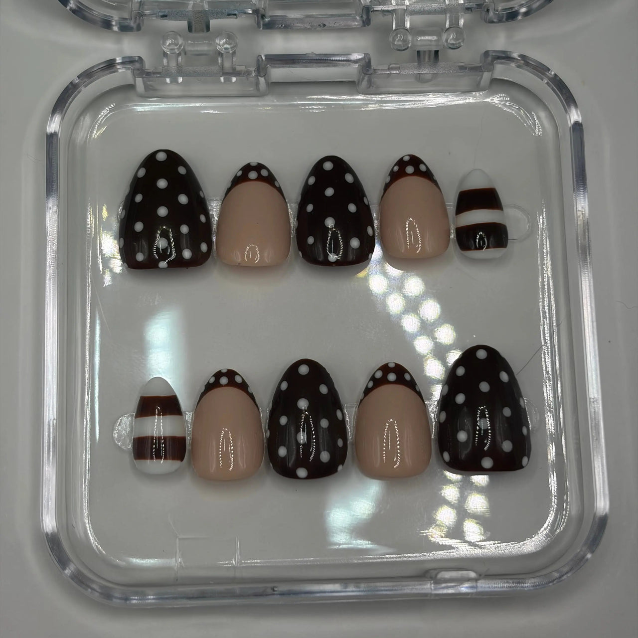 Set of nail art designs in a clear case on a light gray background